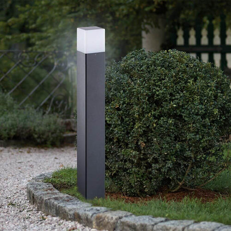 Eckige Pollerleuchte Vadra 80cm IP44 Anthrazit, Weiß steht neben einer Hecke im Garten.