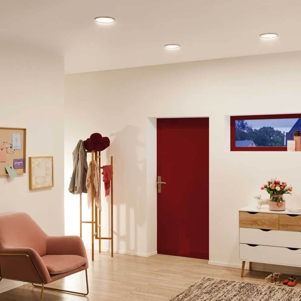 Moderne Wohnung mit ultraflachem LED-Panel, stilvollem Mobiliar und roter Tür in neutralweißer Beleuchtung.