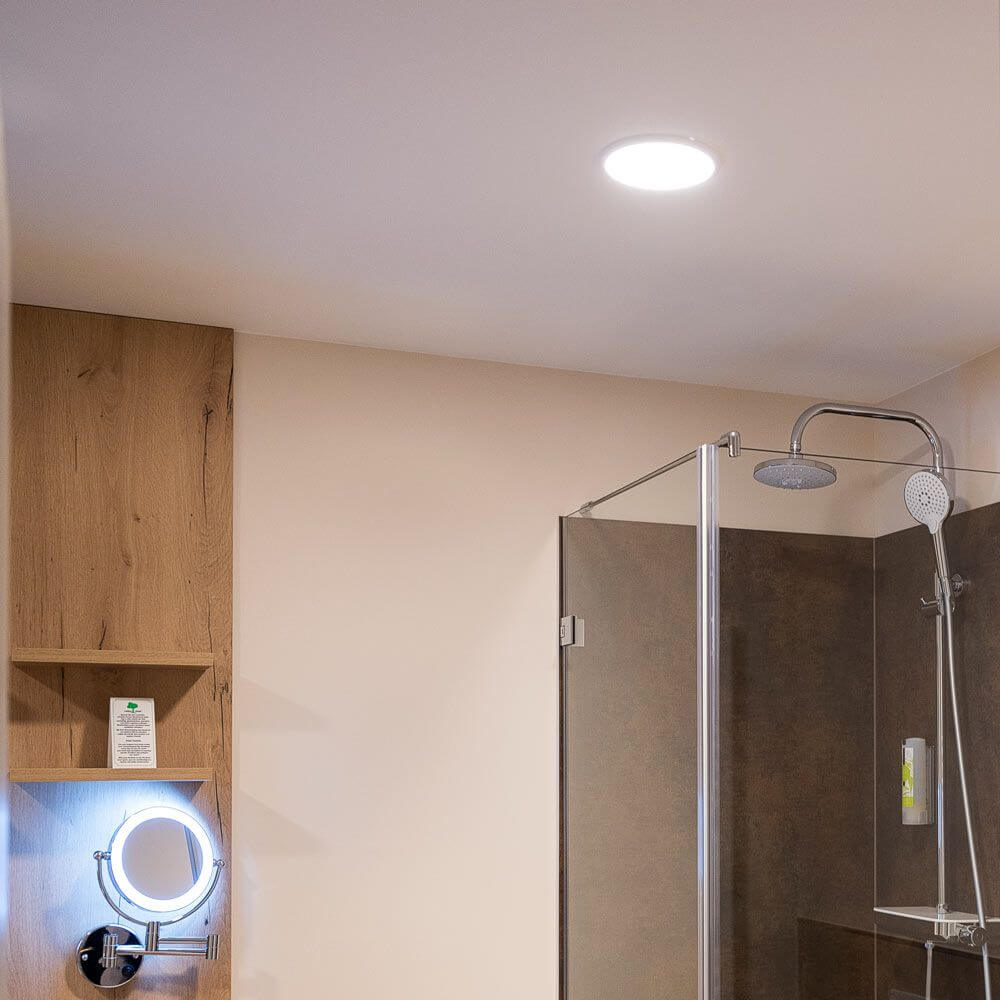 Ultraflaches dimmbares LED-Panel Ø 23cm in modernem Badezimmer über Dusche installiert.