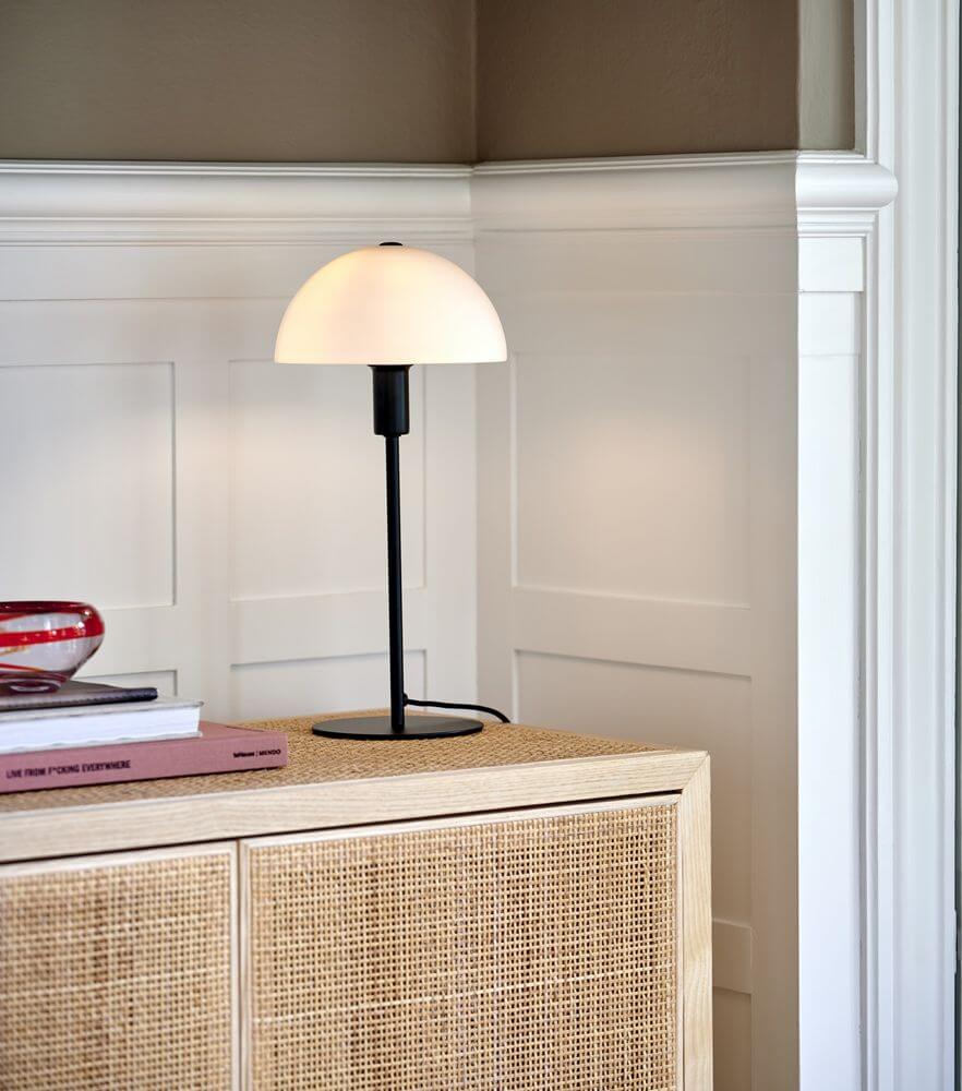 Ellen 20 Tischlampe auf einem Sideboard, minimalistisches skandinavisches Design mit Opalglasschirm.