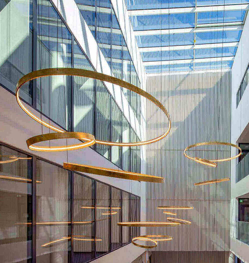 Moderne Beleuchtung mit runden Lampen im Innenhof, große Fenster sorgen für Tageslicht.