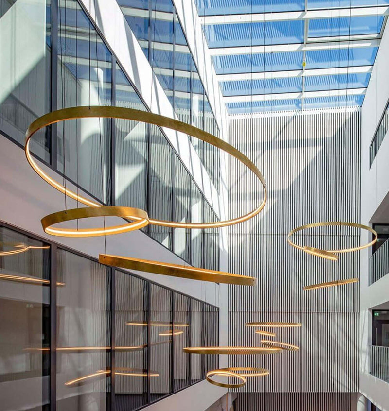 Moderne Beleuchtung mit runden Lampen im Innenhof, große Fenster sorgen für Tageslicht.