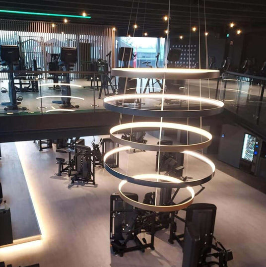 Modernes Fitnessstudio mit stilvollem Ringlicht und funktionalen Trainingsgeräten.