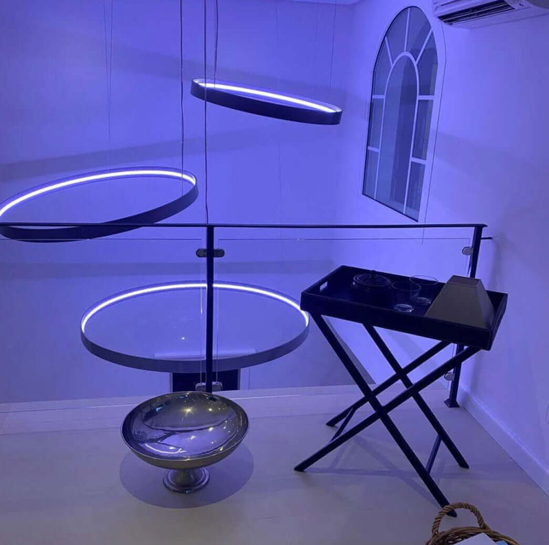 Moderne Innenarchitektur mit schwebenden runden Lampen und stilvollem Tisch im blauen Licht.