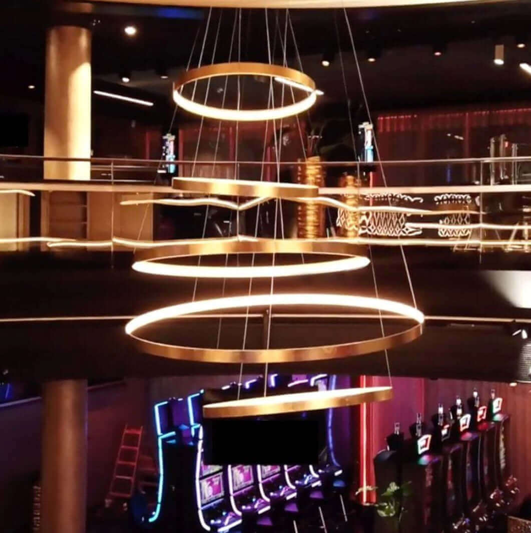 Moderne LED-Deckenleuchte in einem Casino mit Spielautomaten im Hintergrund, stilvolles Interieur.