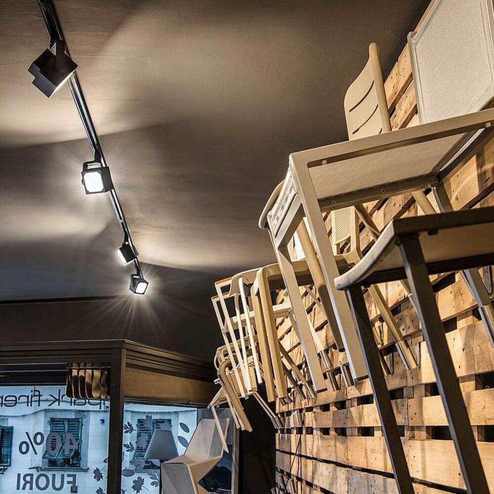 Moderne Euro Cube LED Spots an einer Decke mit dekorativen Stühlen, ideal für Laden- und Messebau.