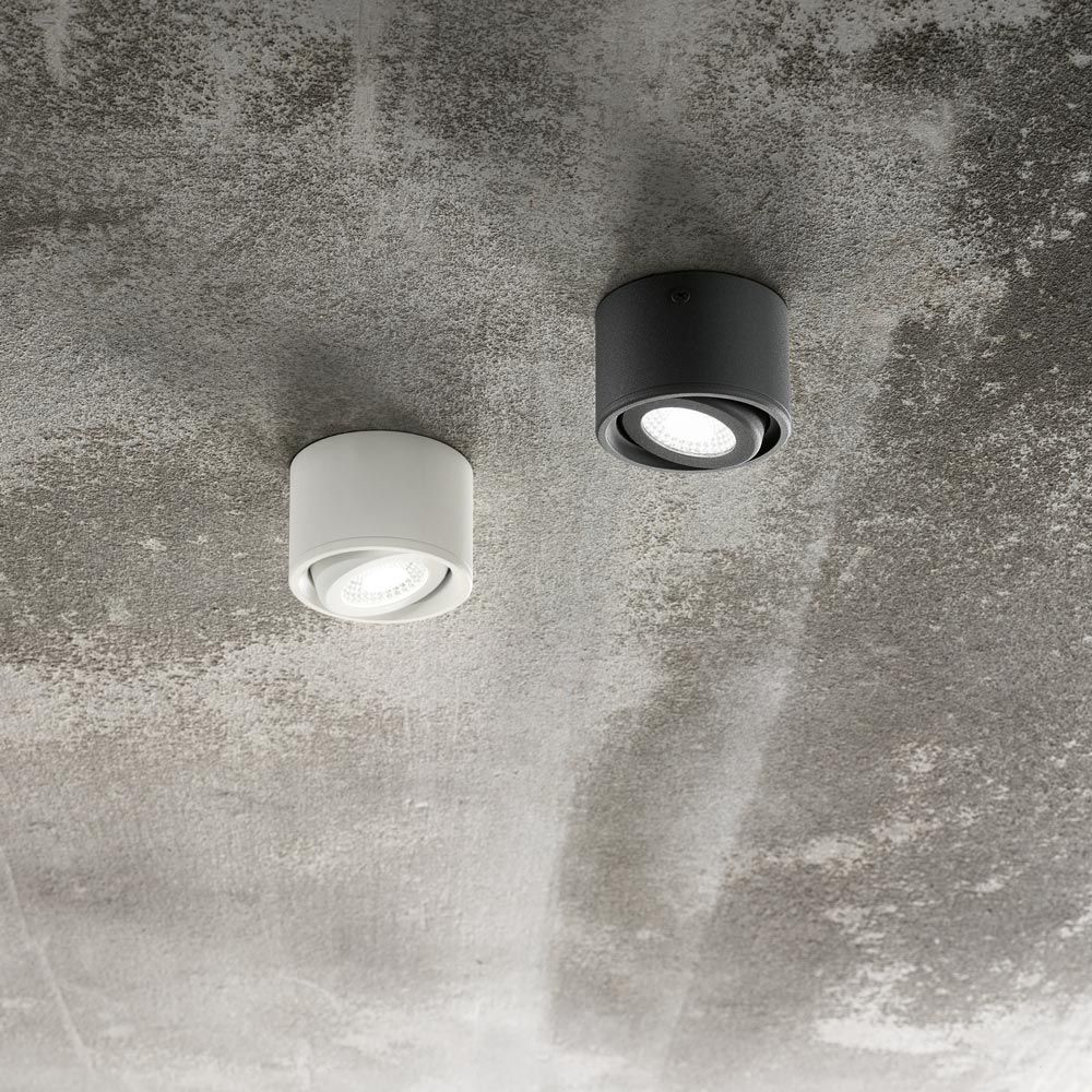 Anzio Spot Weiß und schwarzer Aufbau-Spot an einer grau strukturierten Decke, moderne LED-Leuchten.