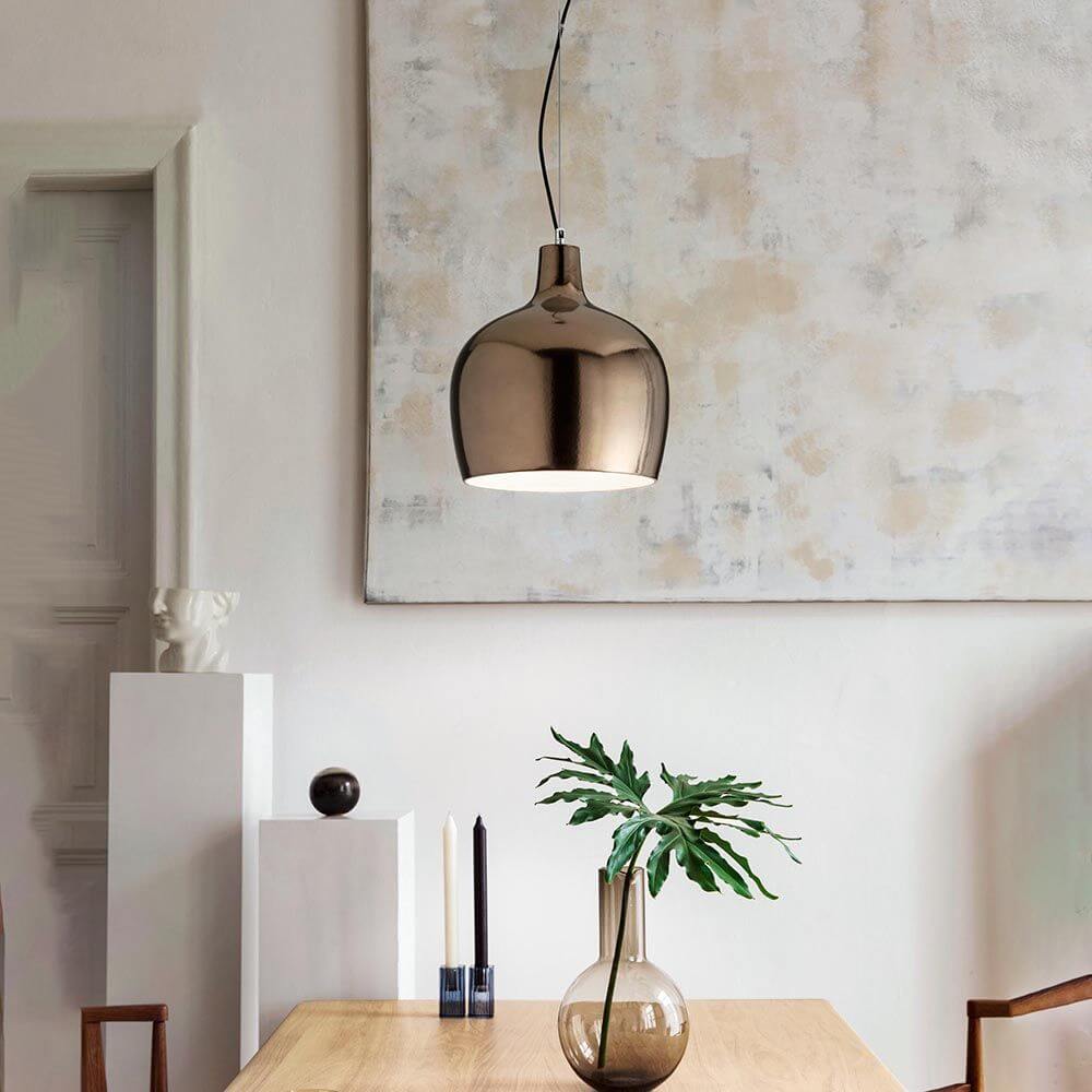 Glossy Pendelleuchte Metall über einem Holztisch mit Dekoration und Pflanzen im modernen Wohnraum.