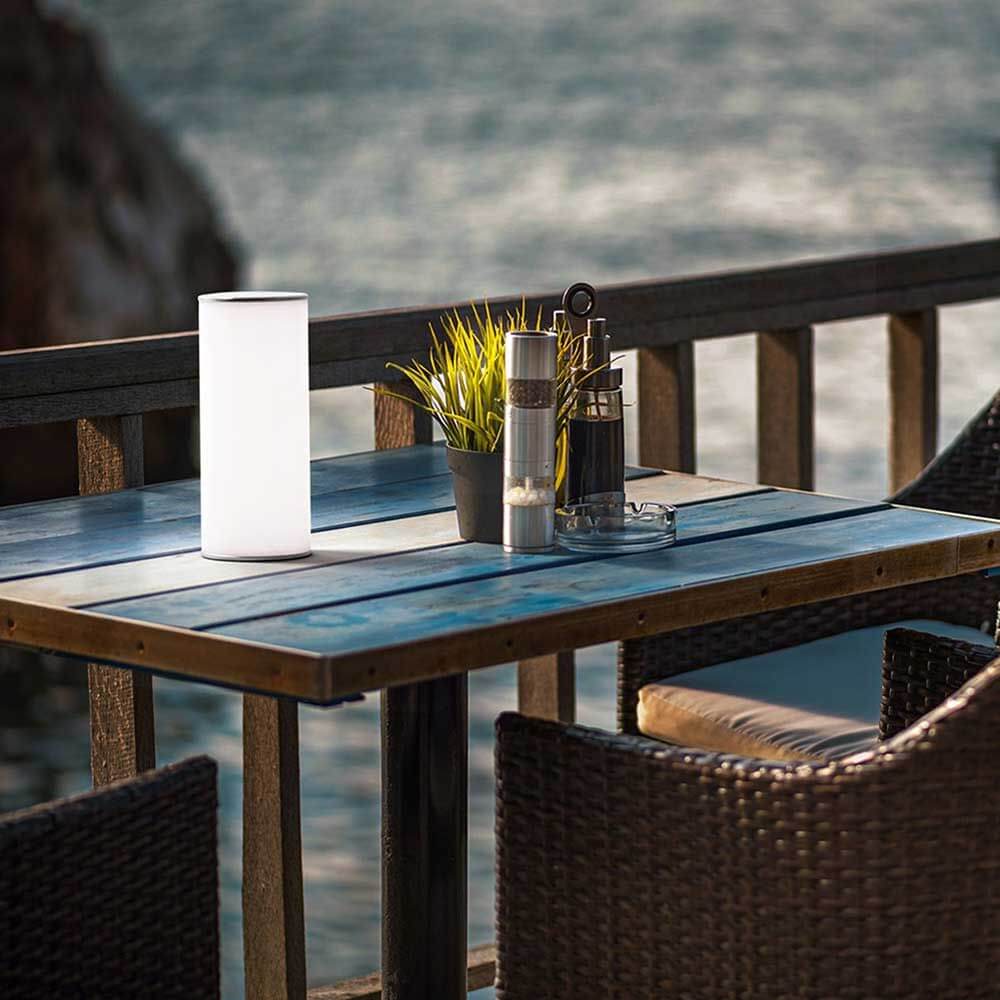 LED Akku Tischleuchte Thalia auf einem Tisch mit Blick auf das Wasser.