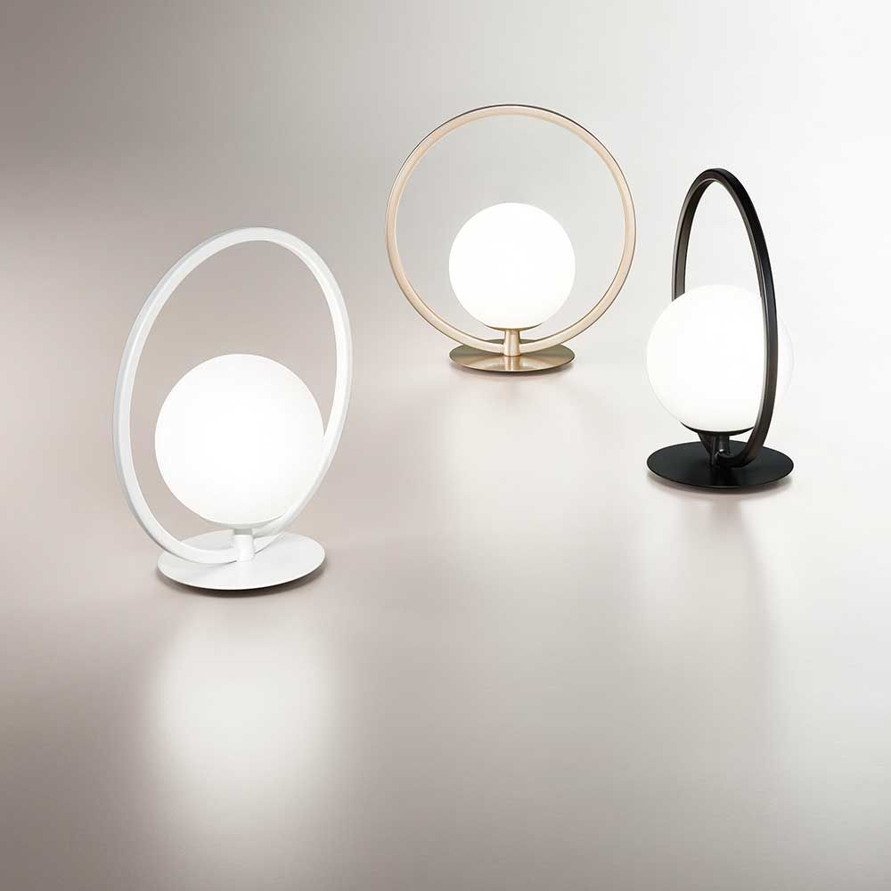 LED Tischlampe Sirio Rund in drei Farben: Weiß, Gold und Schwarz, moderne Tischbeleuchtung auf elegantem Tisch.