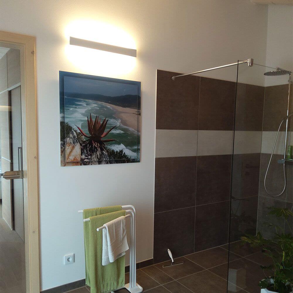 LED Wandleuchte Lotus Aluminium im modernen Badezimmer mit Kunstwerk.
