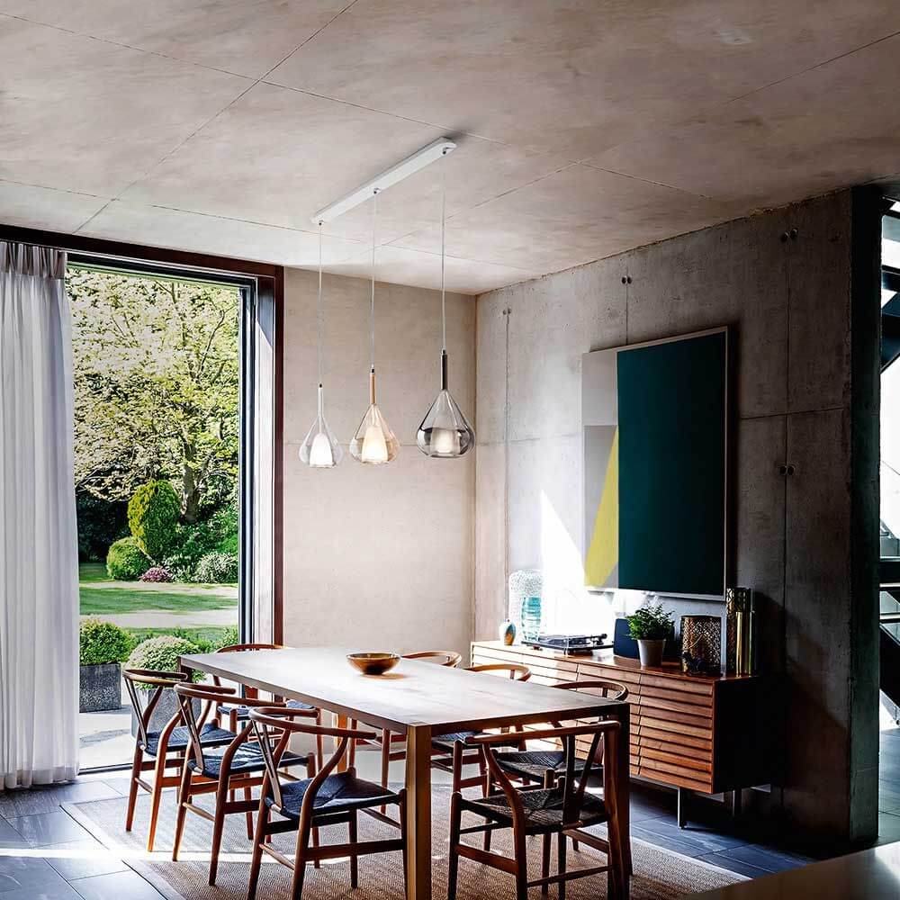 Lila Pendelleuchte aus Metall im modernen Esszimmer mit Holztisch und großen Fenstern.