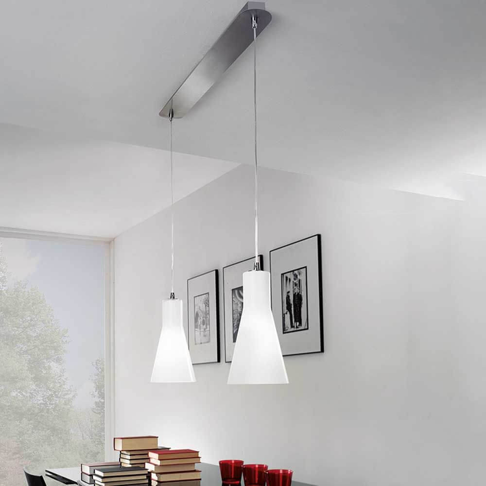 Pendelleuchte Diana in Chrom über einem Tisch mit Bücherstapel und roten Tassen.