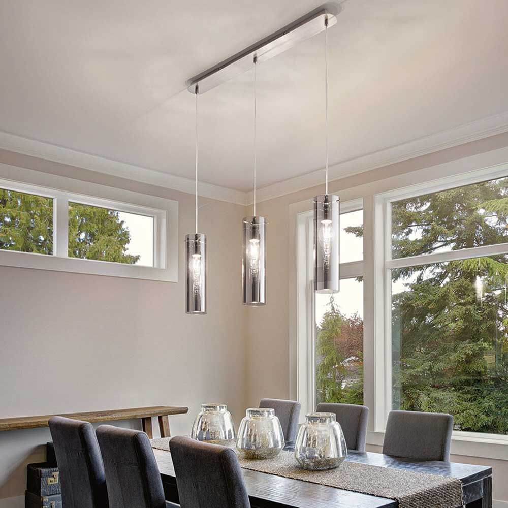 Pendelleuchte Sintesi 3-flammig über einem modernen Esszimmer Tisch mit fünf Stühlen.