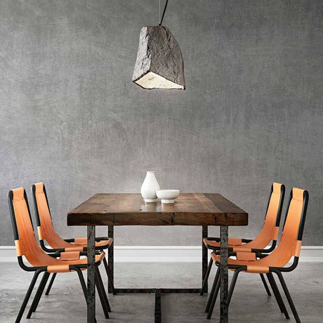 Rock Pendellampe aus Metall über einem holzfarbenen Tisch mit orangefarbenen Stühlen.