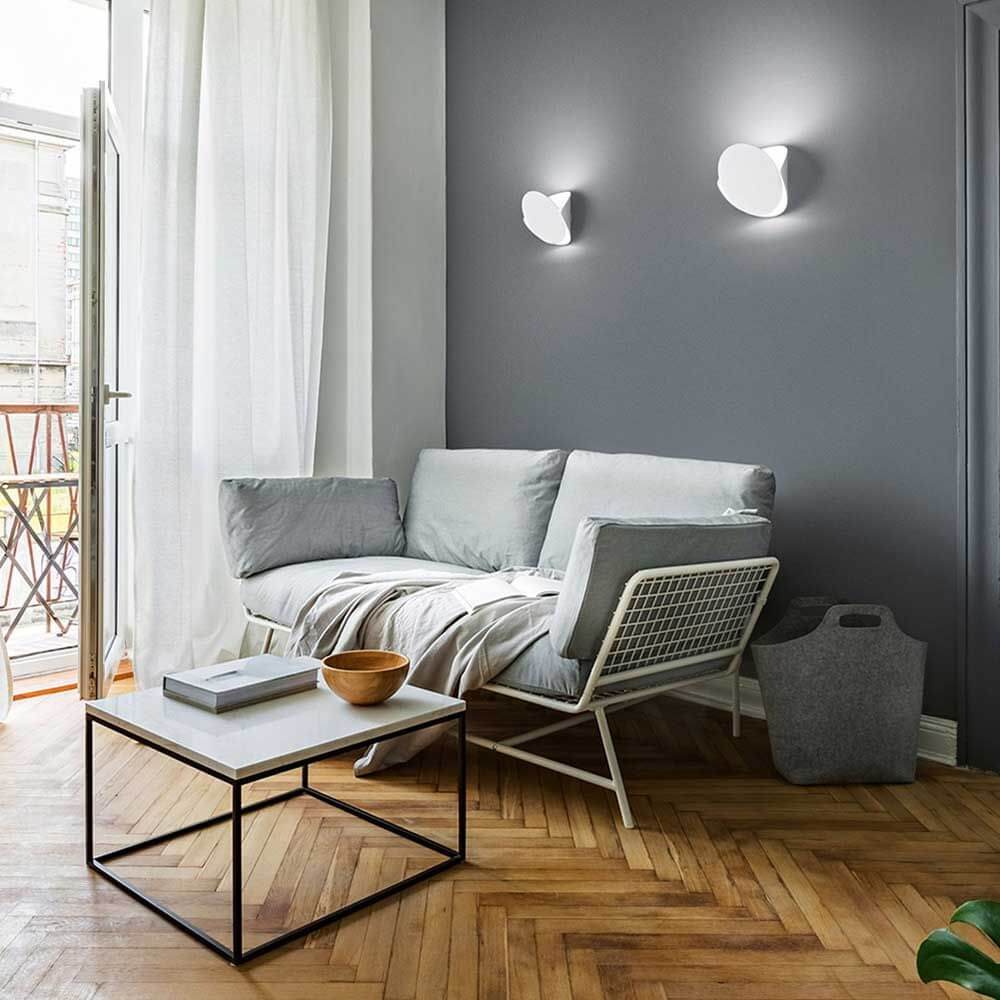 Moderne Wohnatmosphäre mit Shield LED Wandleuchte aus Metall über einem hellen Sofa und Couchtisch.
