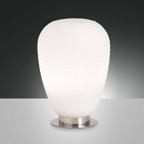 Bordlampe Cora hvit på et bord, ideell for dekorativ belysning i stuen.