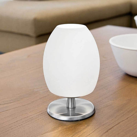 Bordlampe Rockford hvit på et trebord ved siden av en skål, moderne design for stilfull belysning.