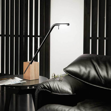 Viktor LED Tischleuchte aus Metall & Holz elegant neben einem bequemen schwarzen Sofa platziert.
