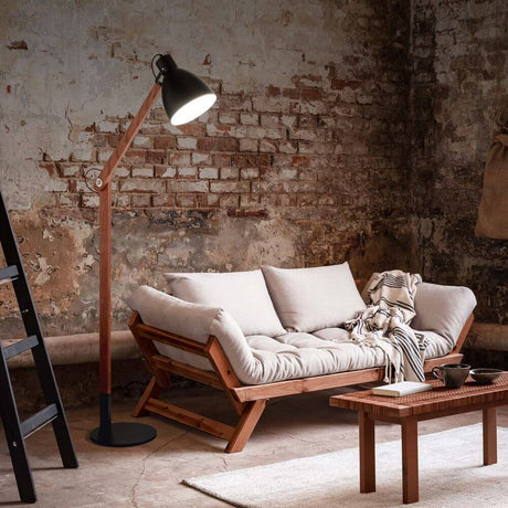 Klassische Leseleuchte Sveva neben einem modernen Sofa in einem rustikalen Raum.