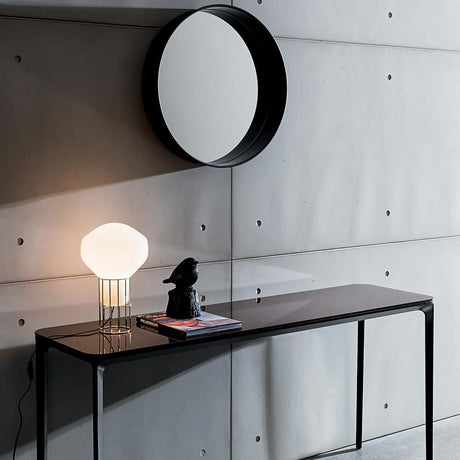 Fabbian Aérostat table lamp Ø 11 cm on a modern table in front of a concrete wall.