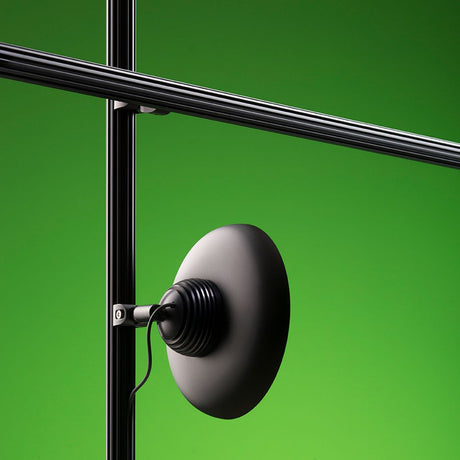 Fabbian Freeline LED track light Ø 15 cm black mounted on a black track system against a green background.
