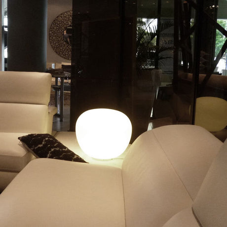 Lampe de table Fabbian Lumi Mochi Ø 20 cm sur un canapé blanc dans un salon moderne.