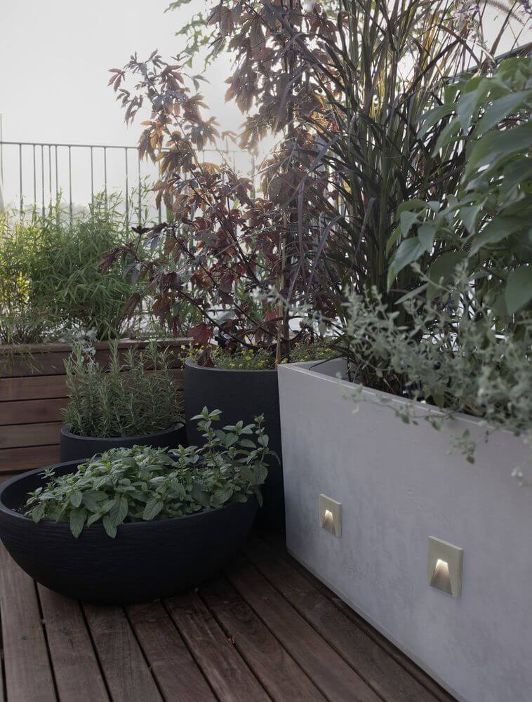 Finlo LED Außenwandeinbauleuchte Lichtauslass Kegel Grau IP65 an einer Terrasse mit Pflanzen.