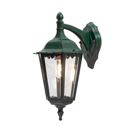 Lampa ścienna Firenze z latarnią na dole w kolorze zielonym zamontowana na ścianie z dekoracyjnym wzorem.