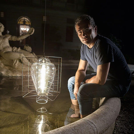 Lampe suspendue d’extérieur Attimo IP44 en verre de Murano qui brille dans un jardin élégant la nuit.