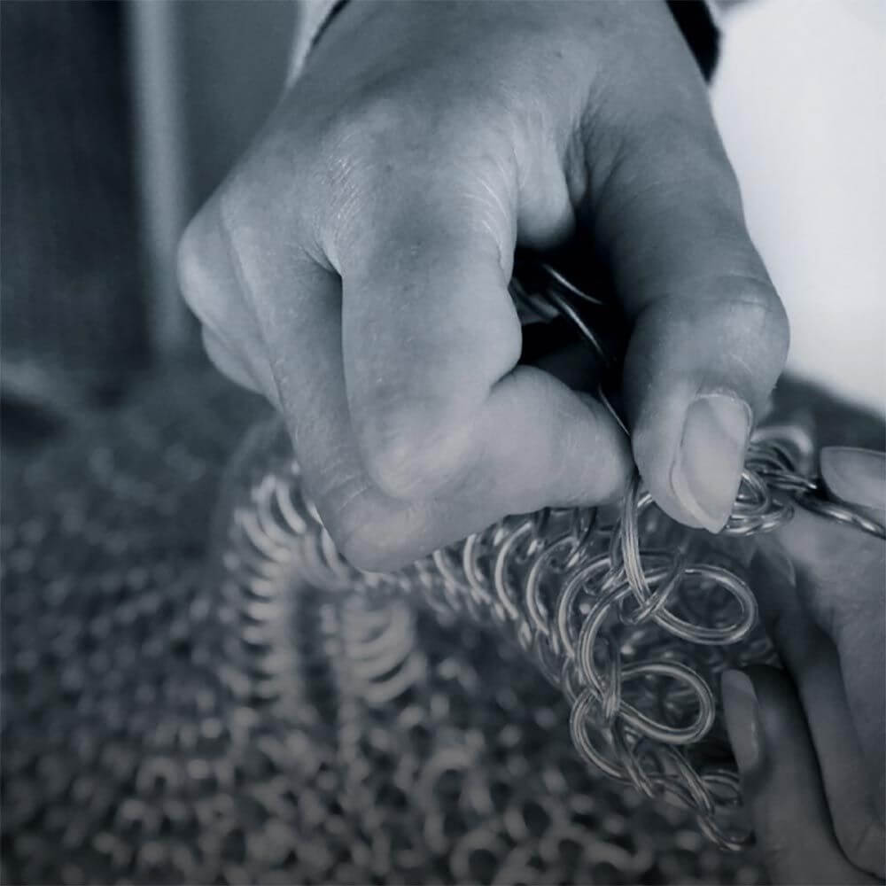 Detailaufnahme der Hand, die Metallketten für die Luce Wandleuchte Rund Ø 34cm verarbeitet.