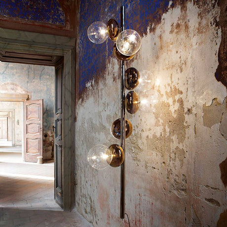 Unica Hänge- & Stehleuchte 6-flammig an einer Wand mit bezauberndem Design und goldenen Glaselementen.