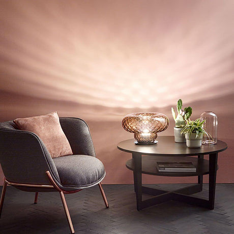 Versi Tischleuchte venezianisches Glas auf einem Tisch neben einem Stuhl und Pflanzen, strahlendes Lichtmuster.
