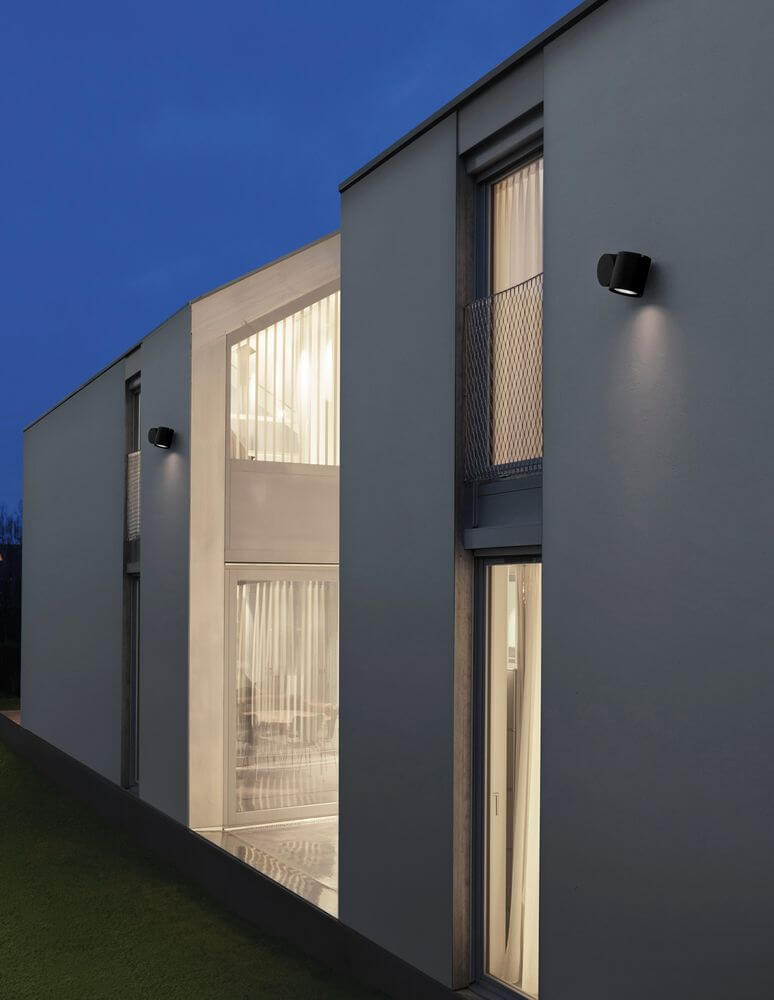 Focus Außenwandleuchte Rund GU10 Schwarz IP54 an moderner Fassade, stilvolle Außenbeleuchtung bei Nacht.