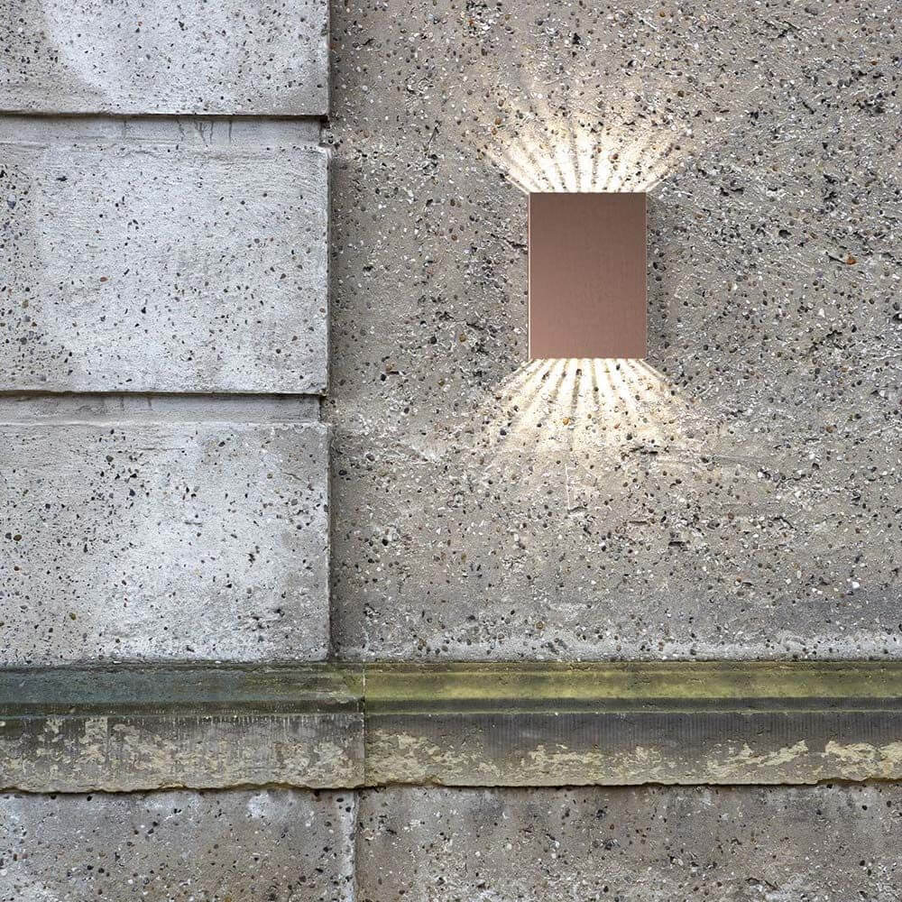 Falt 10 LED Außen-Wandleuchte in Kupfer montiert an einer Betonwand mit direkter Ausleuchtung.