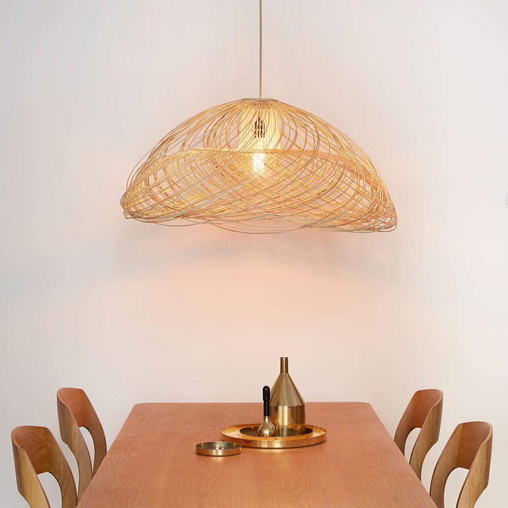 Forestier Rattan-Pendelleuchte Satelise über einem Holz-Tisch, dekoriert mit Tischaccessoires.