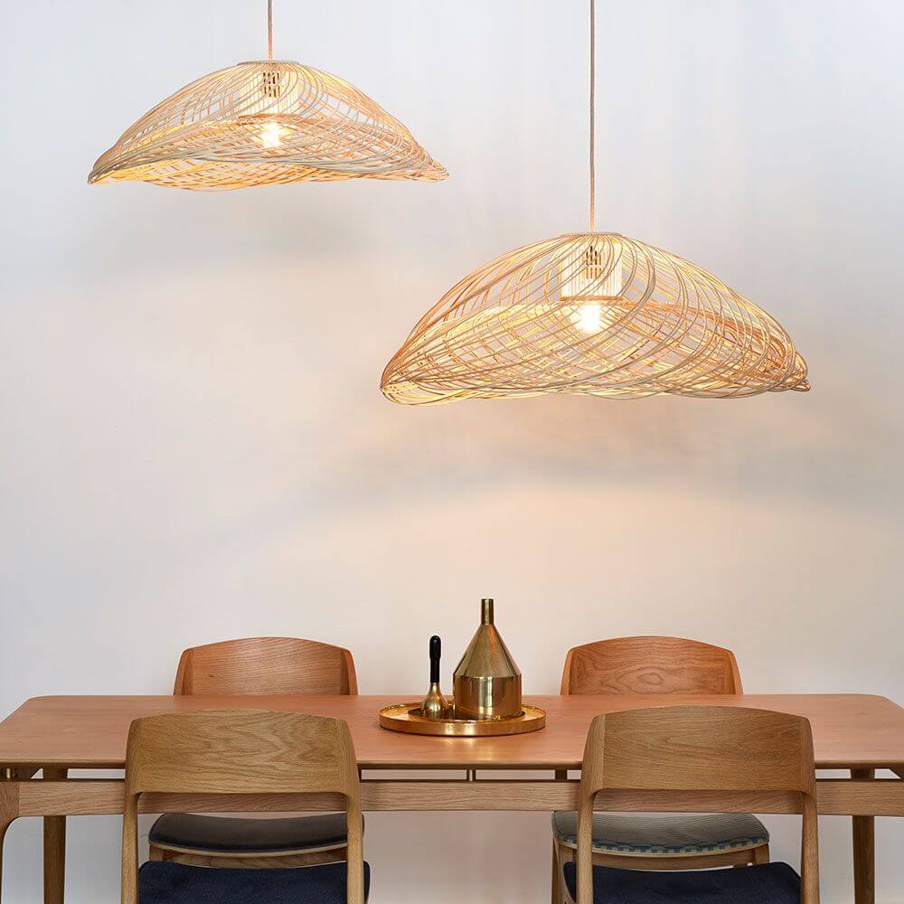 Forestier Rattan-Pendelleuchte Satelise über einem Esszimmertisch mit warmem Licht und Holzstuhl-Arrangement.