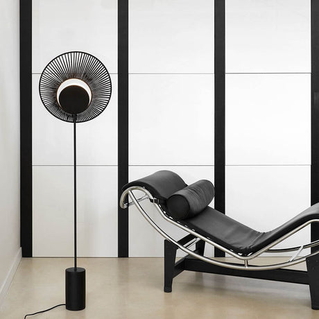 Forestier Oyster floor lamp 145 cm next to a modern black lounge chair in a minimalist room.