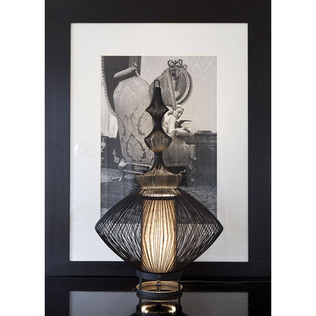 Forestier Opium table lamp with metallic wires and elegant design, in the foreground in front of a nostalgic image.