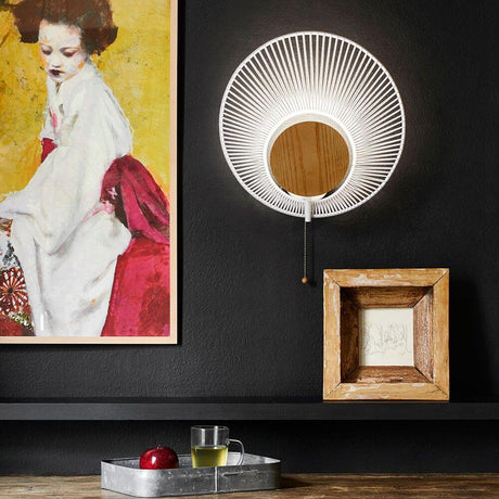 Forestier Wandleuchte Oyster mit Zugkabel an einer dunkel gestrichenen Wand, umgeben von Kunstwerken.