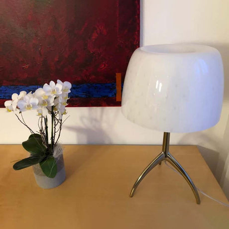 Lumiere 30th Grande Tavolo bordlampe hvit ved siden av en orkidé på et bord, moderne design av Foscarini.