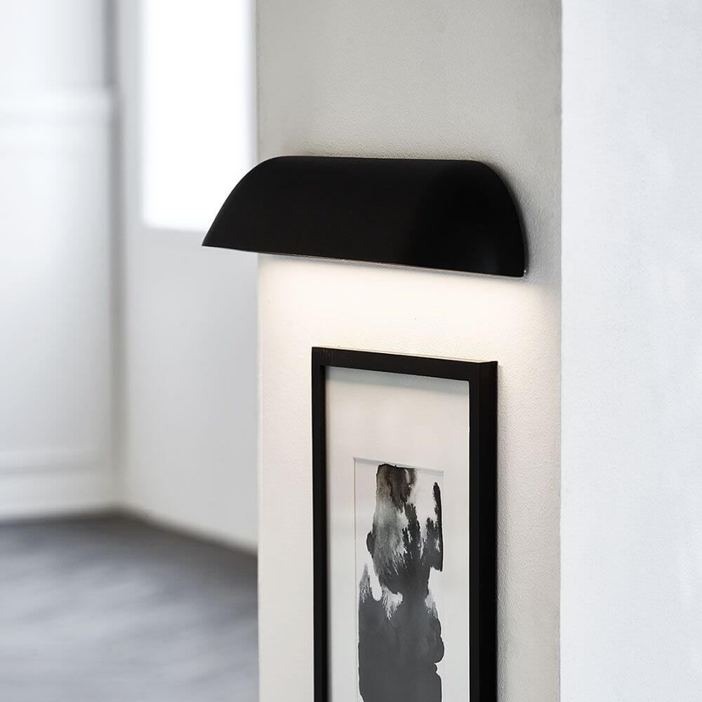 Front 36 LED utendørs vegglampe IP44 svart på en vegg, sterkt lys skinner på et bilde.