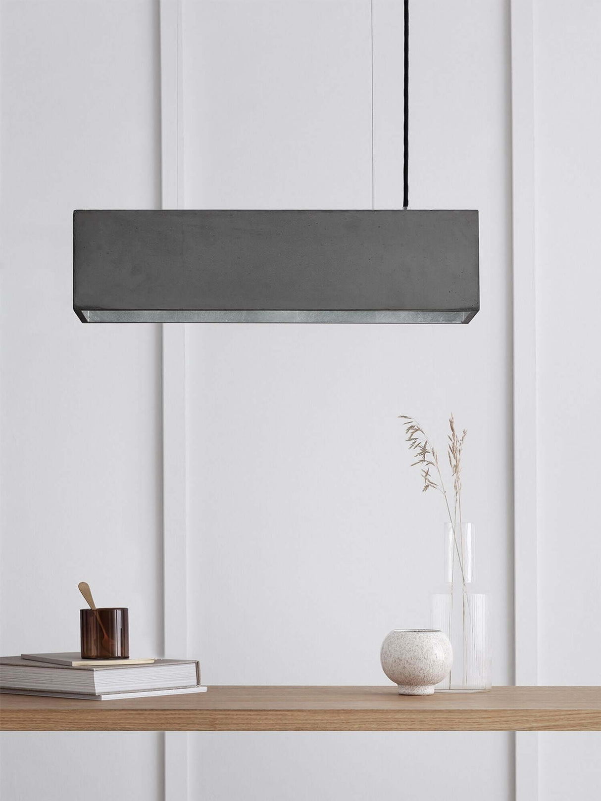 Gantlights B4 LED-Pendelleuchte Beton 56cm dimmbar über einem Tisch mit Dekorationen.