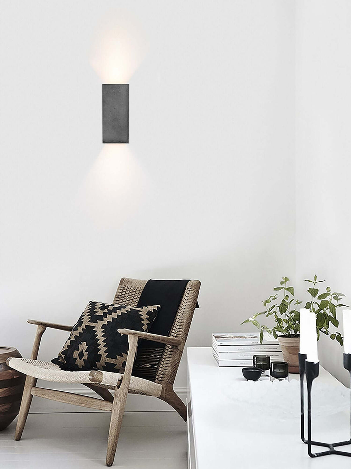 Gantlights B8 Beton Wandlampe rechteckig Up & Down an weißer Wand mit warmem Up‑Down Licht über Sessel und Dekor