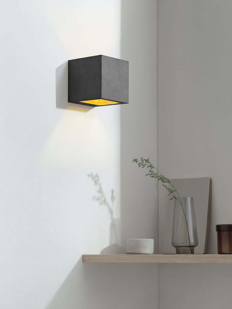 Gantlights B9 Wandleuchte Up & Down an einer Wand, strahlt warmes Licht in einem modernen Raum aus Beton.