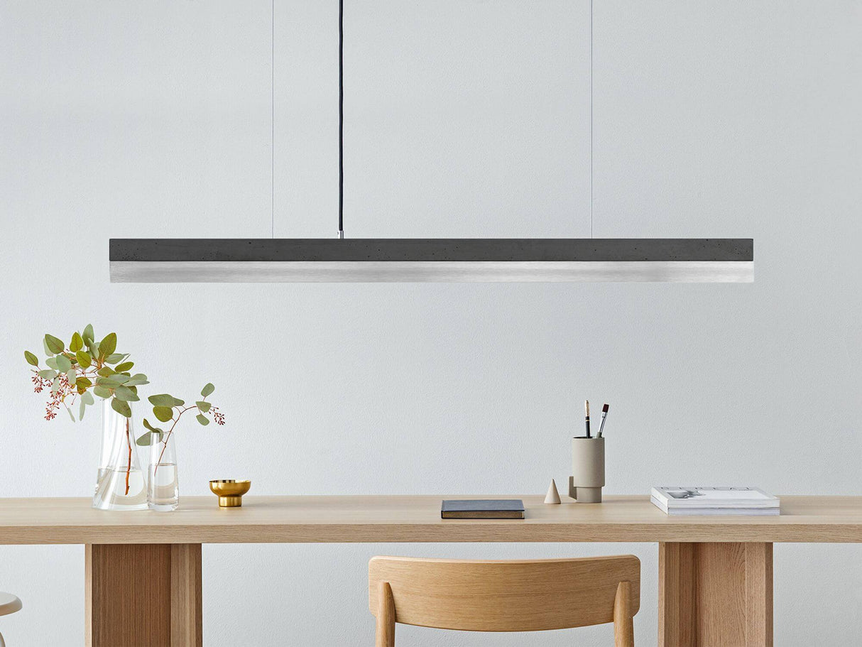 Gantlights C1 LED-Pendelleuchte 122cm Beton Holz über einem modernen Tisch mit Stühlen und Pflanzen.