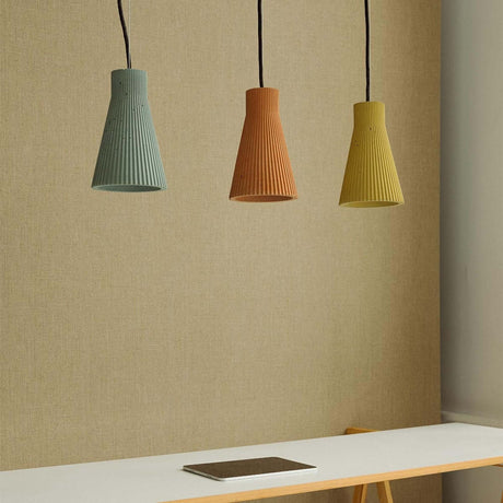 Gantlights S1 betongpendelampe med rillet design i ulike farger henger over et bord.