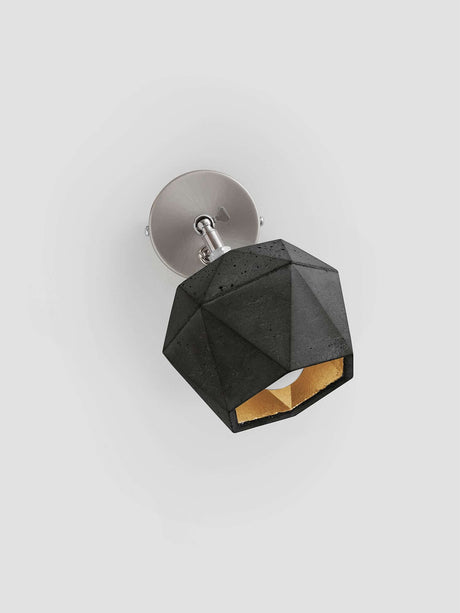 Gantlights T2 Wandspot Beton trianguliert in schwarzem Beton mit goldener Innenbeschichtung.