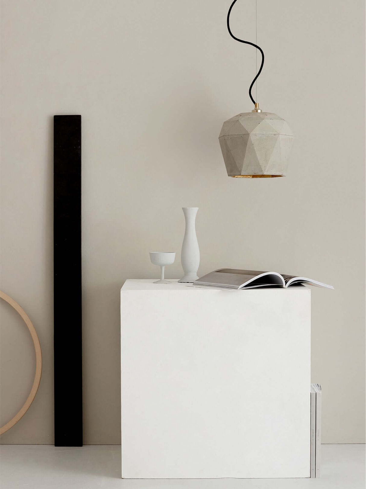 Gantlights T4 Hängeleuchte Beton über einem minimalistischen Tisch mit Vasen und Magazinen.