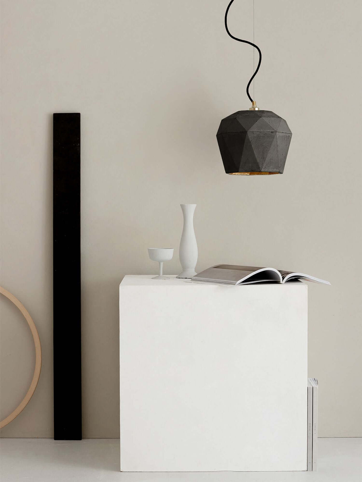 Gantlights T4 Hängeleuchte Beton über einem weißen Tisch mit Dekoration.